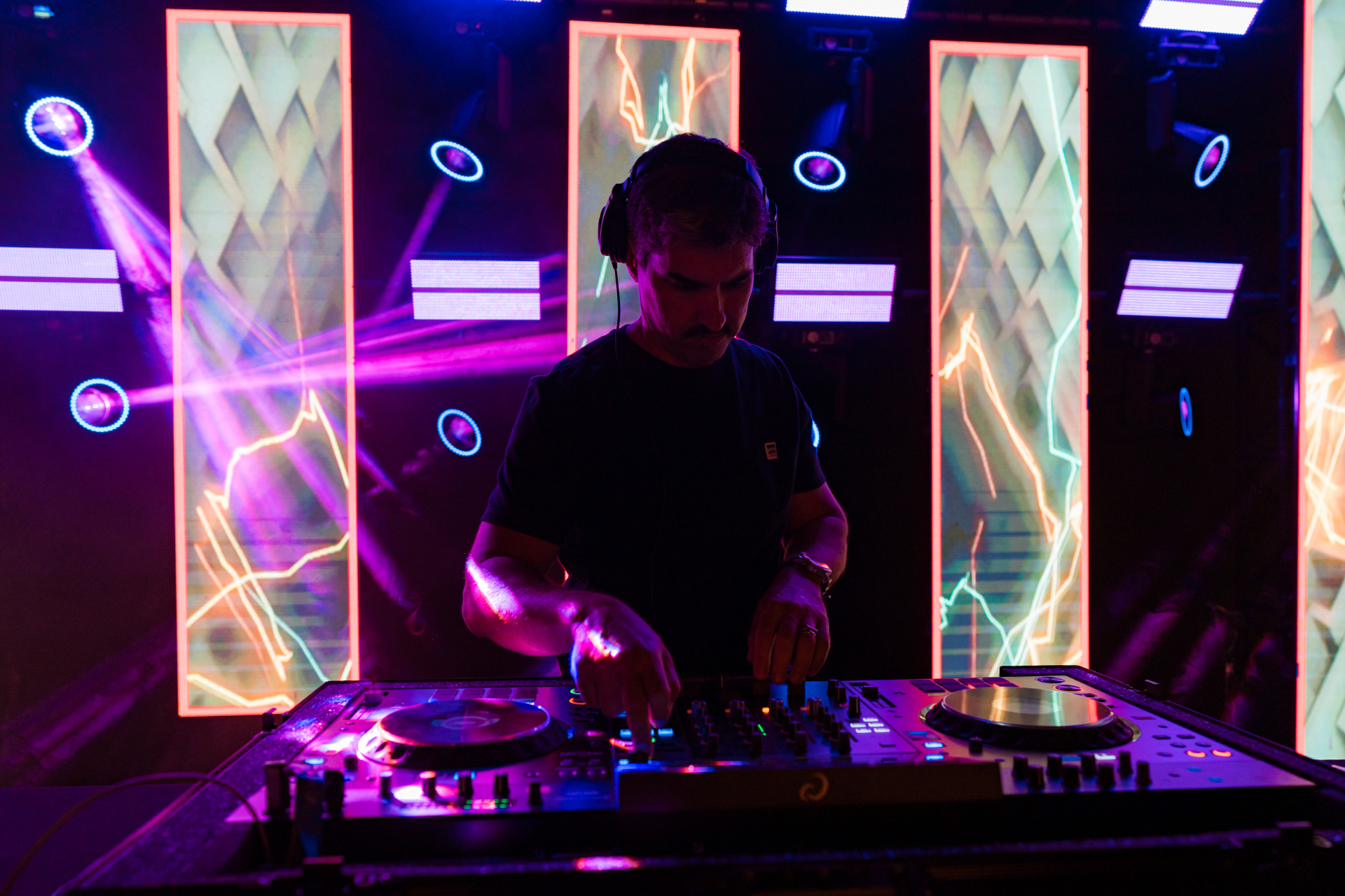 DJ comandando a pista com painéis de LED e luzes cênicas