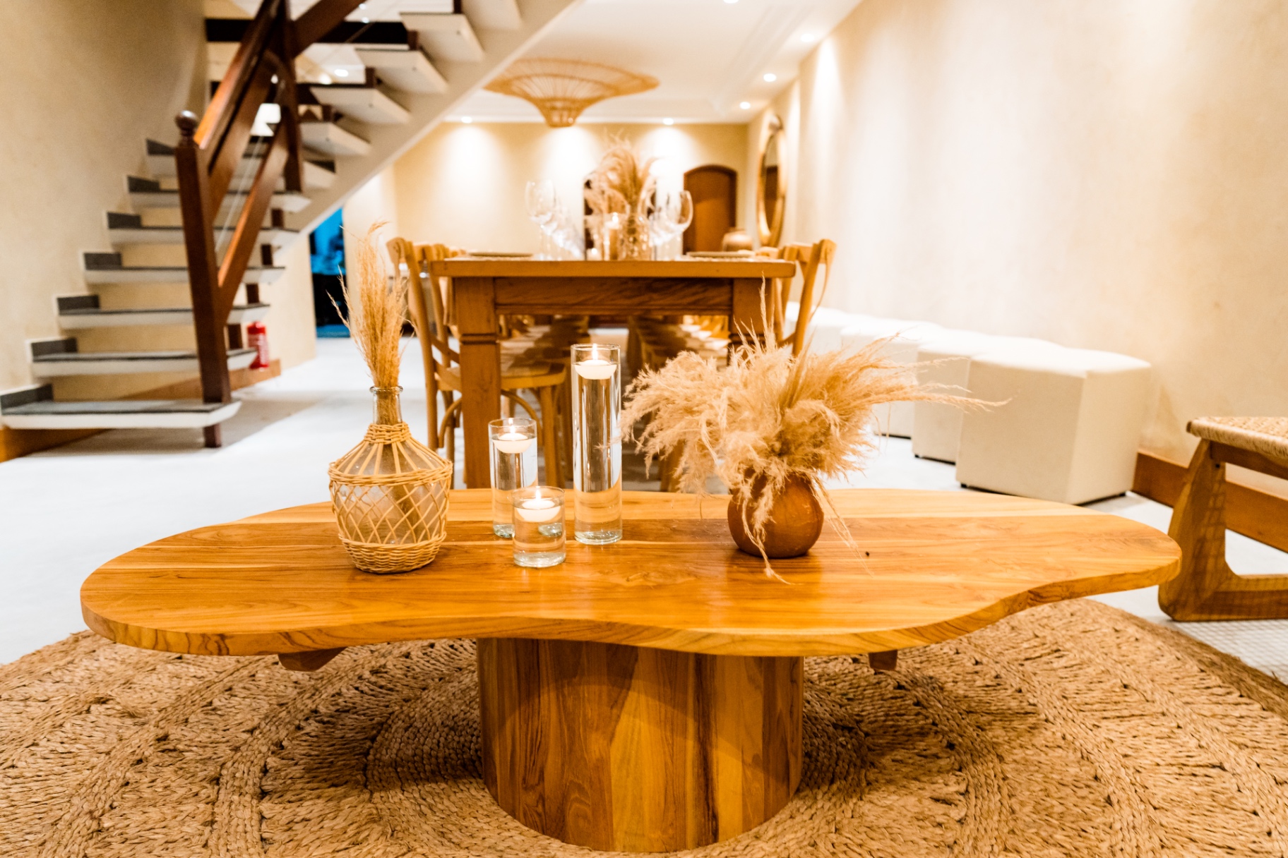 Sala de estar com mesa orgânica de madeira, velas e capim dos pampas